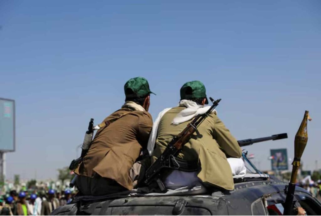 Houthi-mobilized fighters ride atop a car in Sanaa, Yemen