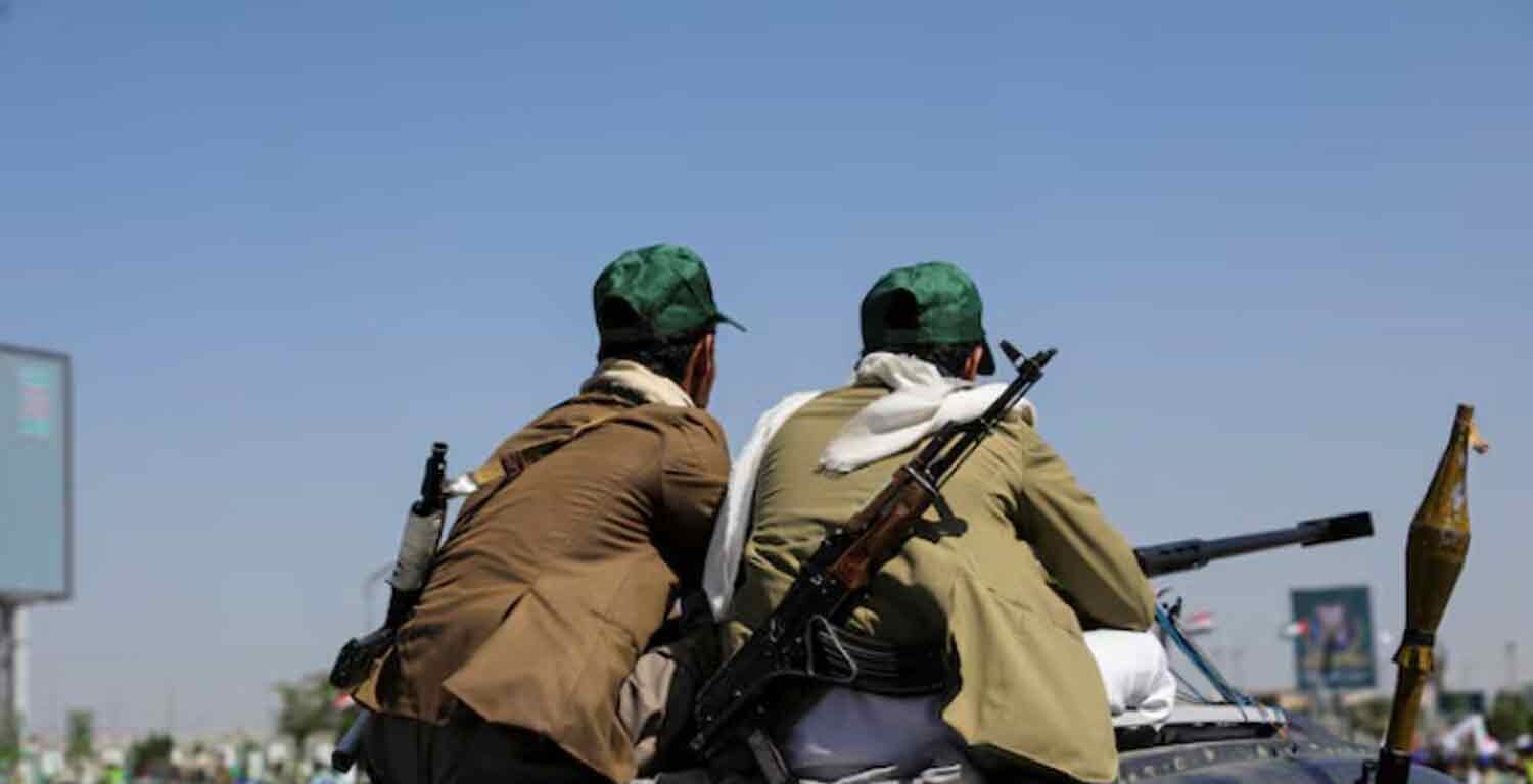 Houthi-mobilized fighters ride atop a car in Sanaa, Yemen