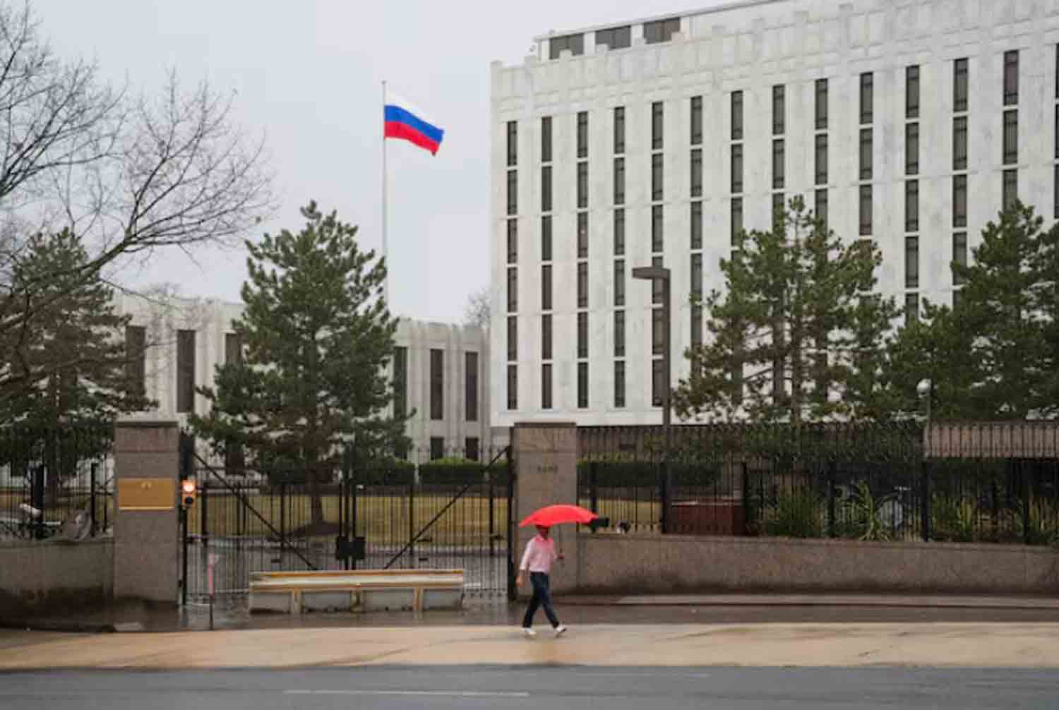 A pedestrian walks with an umbrella outside the Embassy of the Russian Federation, near the Glover Park neighborhood of Washington, U.S.