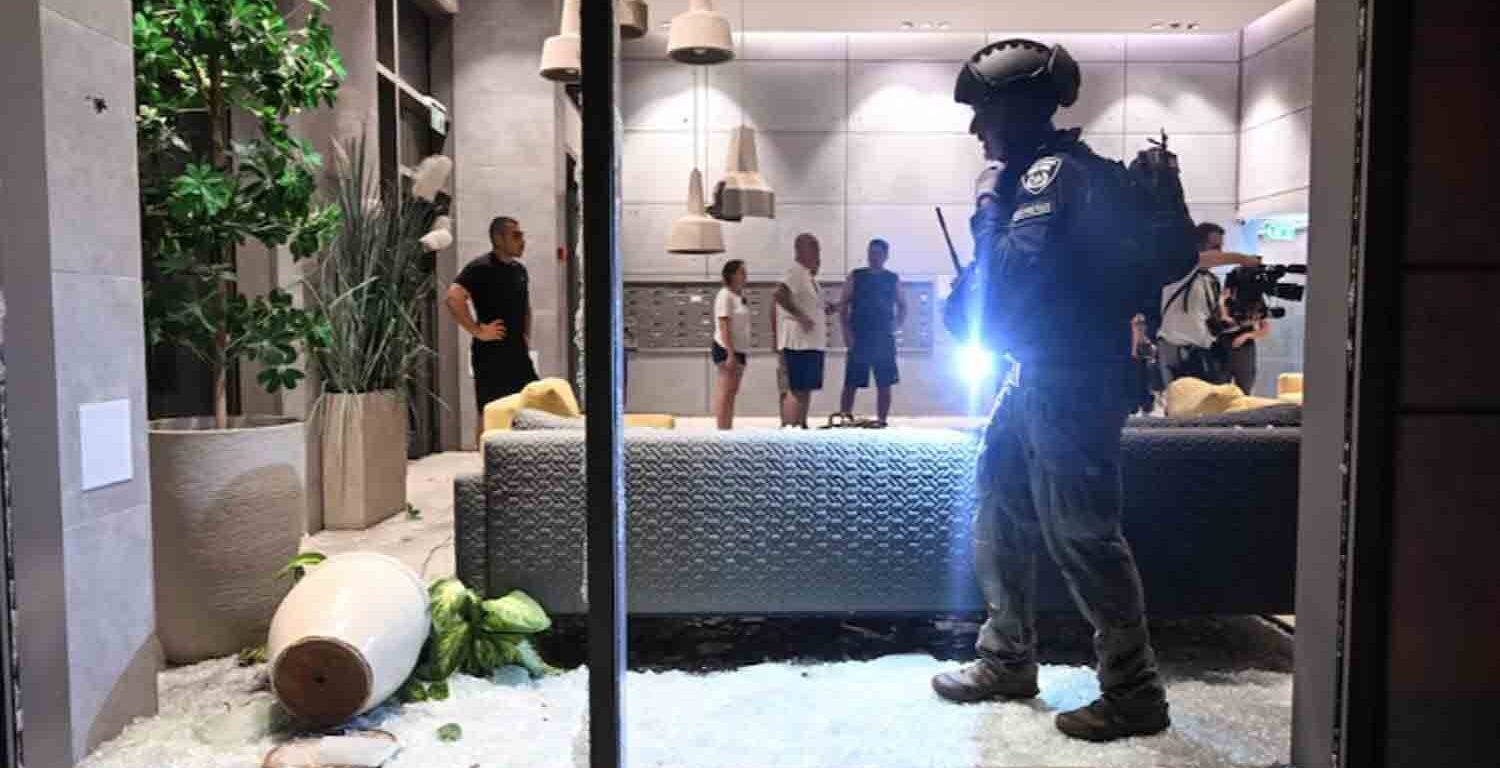 An Israeli police officer inspects the damage to a residential building caused by a rocket fired towards Israel from Lebanon, amid cross-border hostilities between Hezbollah and Israel, in Haifa, Israel.