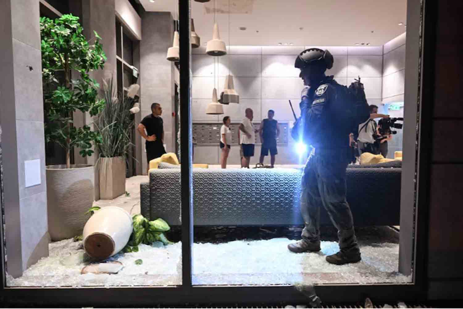 An Israeli police officer inspects the damage to a residential building caused by a rocket fired towards Israel from Lebanon, amid cross-border hostilities between Hezbollah and Israel, in Haifa, Israel.