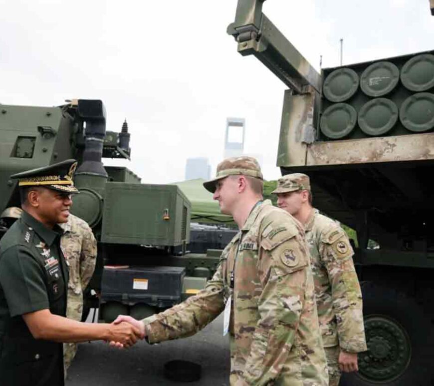 Philippine military chief Gen. Romeo Brawner Jr. left, greets US soldiers beside a HIMARS rocket launcher on display during the Asian Defense and Security Exhibition.