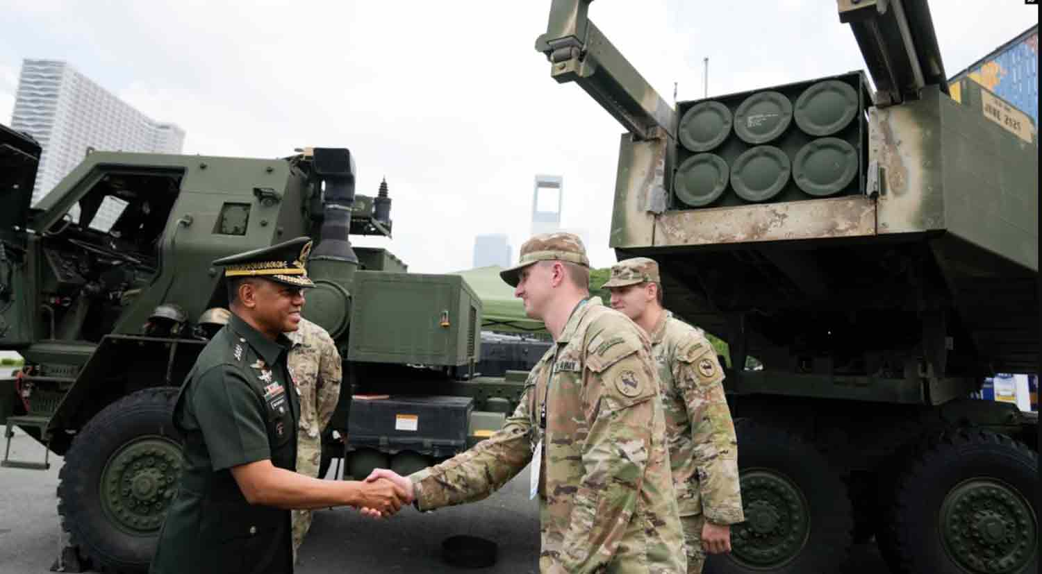 Philippine military chief Gen. Romeo Brawner Jr. left, greets US soldiers beside a HIMARS rocket launcher on display during the Asian Defense and Security Exhibition.