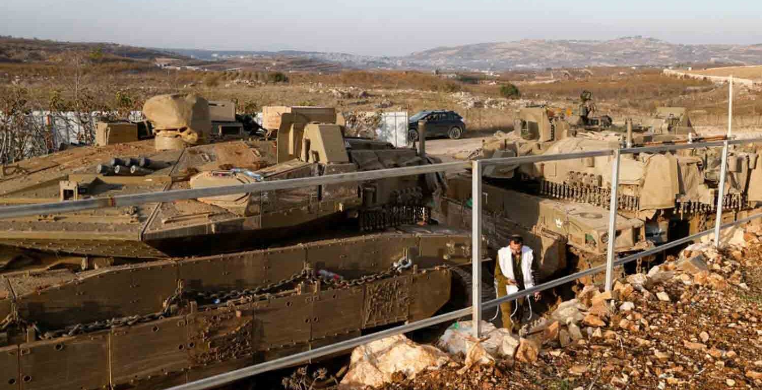 An Israeli soldier walks past tanks deployed near the Israel-Syria border in the Israeli-occupied Golan Heights.