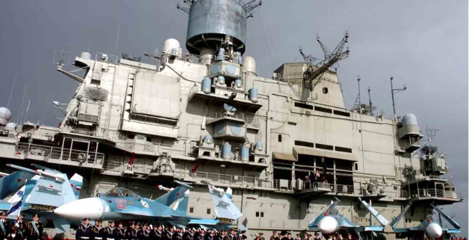 Naval personnel stand in front of the Russian aircraft carrier Kuznetsov in the Syrian city of Tartous on the Mediterranean sea