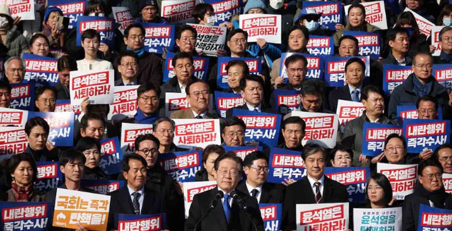 South Korea's main opposition Democratic Party leader Lee Jae-myung looks on as people hold placards that read "Step down President Yoon Suk Yeol" and "Investigate his act of rebellion immediately", at a rally to condemn South Korean President's surprise declarations of the martial law last night and to call for his resignation, at the national assembly in Seoul, South Korea.