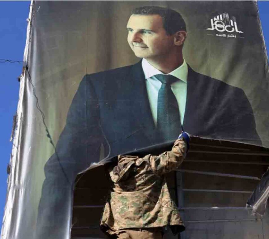 An anti-government fighter tears down a portrait of Syria's President Bashar al-Assad in Aleppo, after jihadists and their allies entered the northern Syrian city.