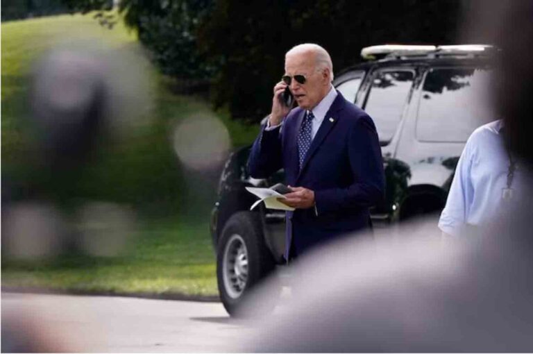 U.S. President Joe Biden talks on a phone while walking towards Marine One as he departs the White House in Washington, U.S.