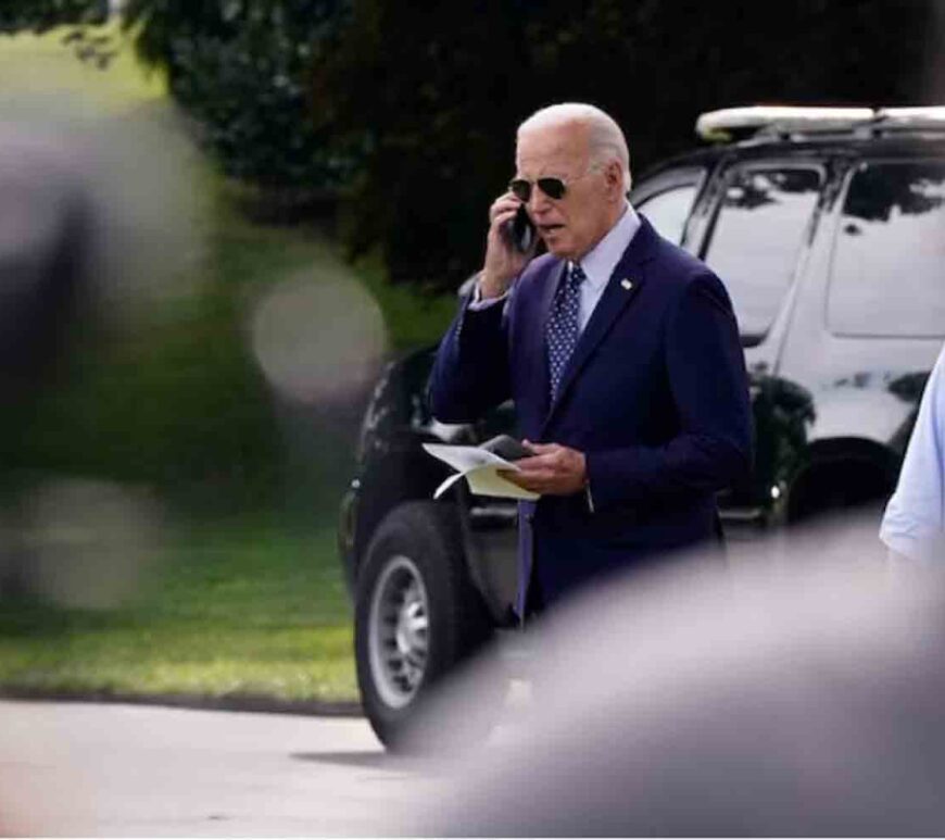 U.S. President Joe Biden talks on a phone while walking towards Marine One as he departs the White House in Washington, U.S.