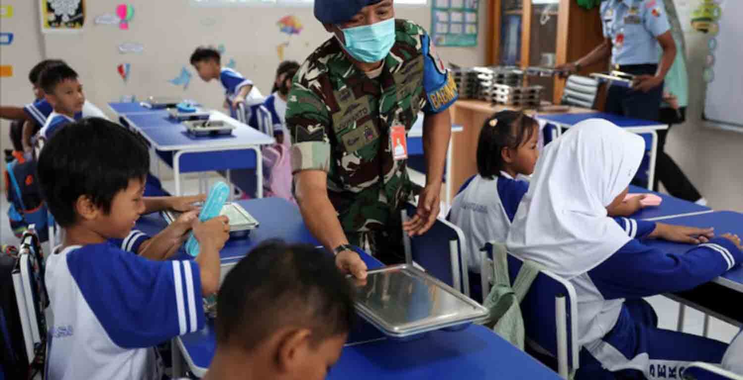 Indonesian Air Force personnel Juwanto offers a meal box to a student at the elementary school Angkasa 5 in Jakarta, Indonesia.