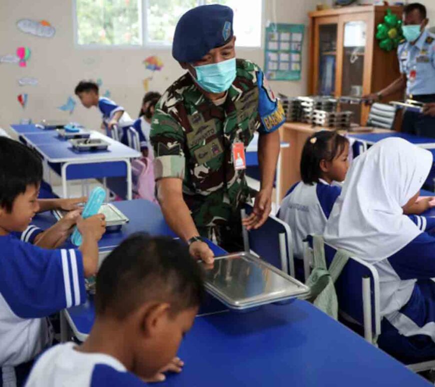 Indonesian Air Force personnel Juwanto offers a meal box to a student at the elementary school Angkasa 5 in Jakarta, Indonesia.