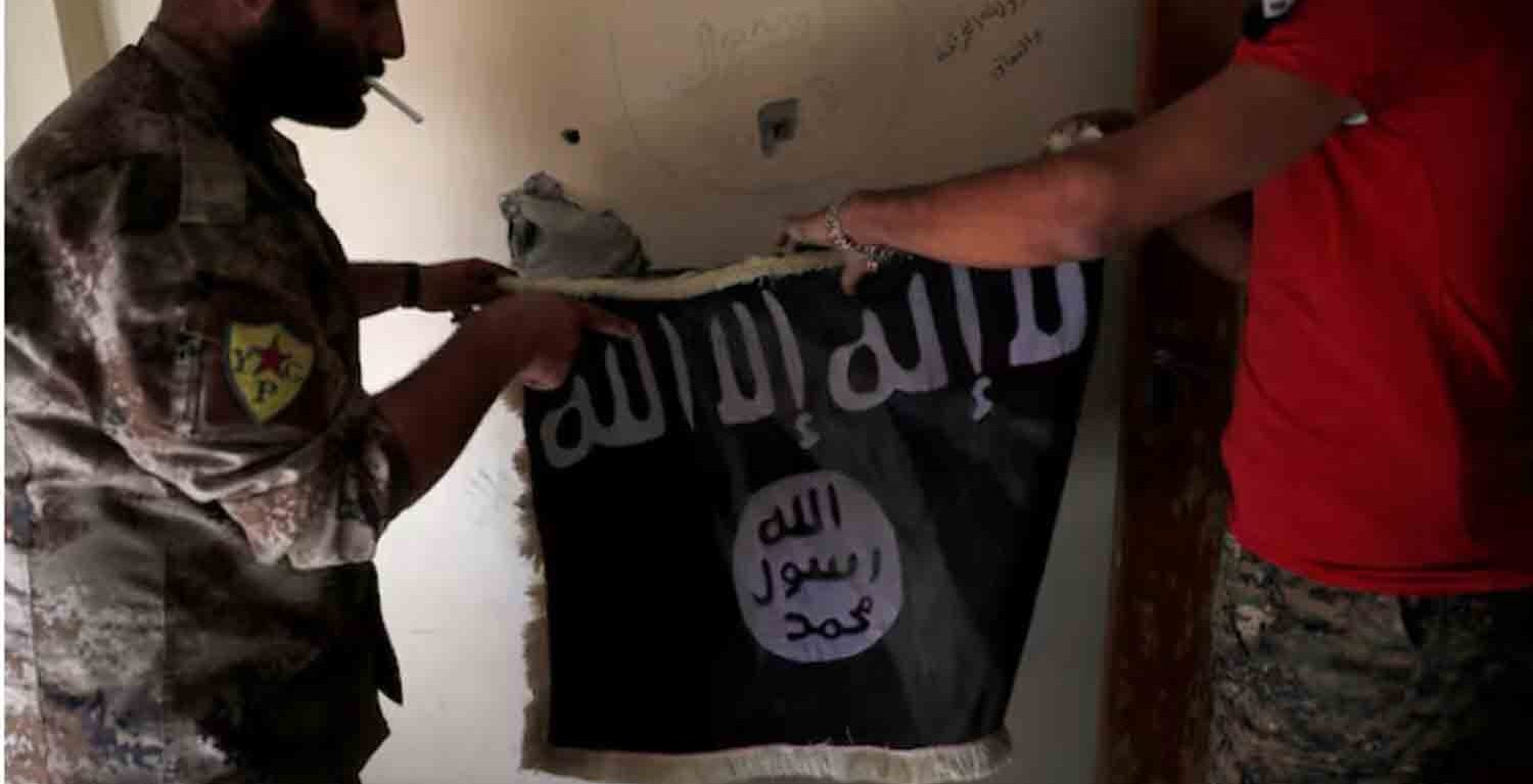 Members of Syrian Democratic Forces hold a flag of the Islamic State militants recovered at a building next to the stadium in Raqqa, Syria.