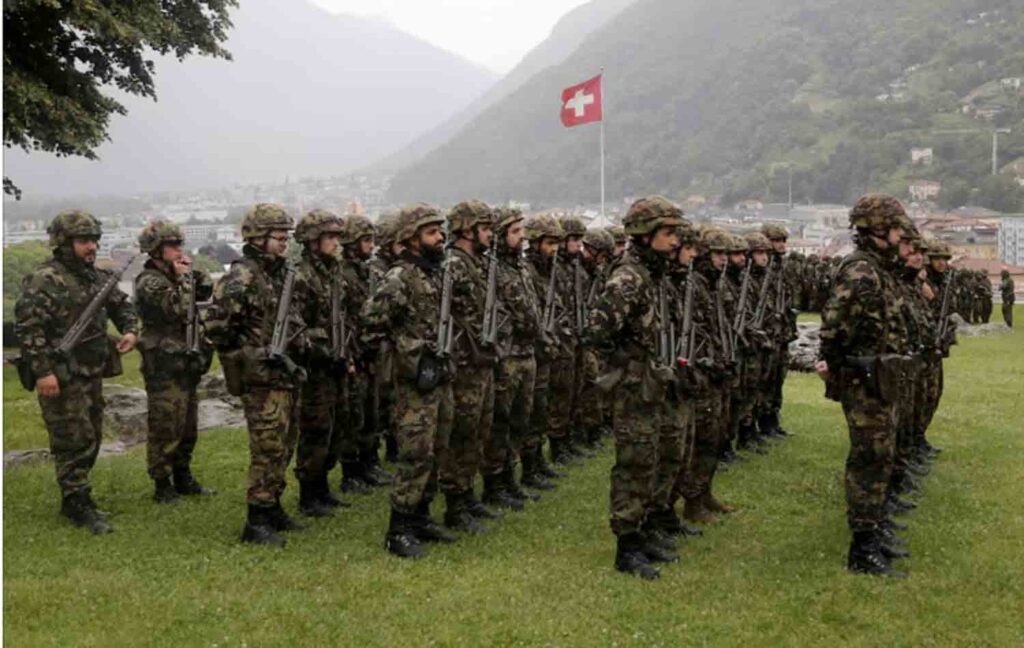 Switzerland's national flag flies behind soldiers of the Swiss Army's 21st Signal Battalion before a ceremony at the medieval Castelgrande castle in Bellinzona, Switzerland.