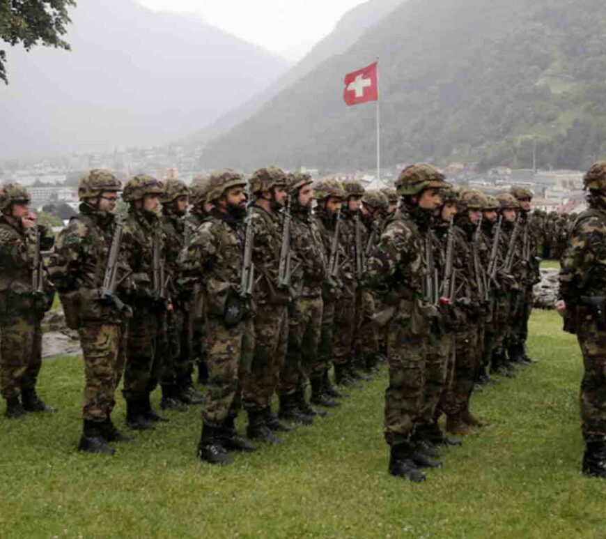 Switzerland's national flag flies behind soldiers of the Swiss Army's 21st Signal Battalion before a ceremony at the medieval Castelgrande castle in Bellinzona, Switzerland.