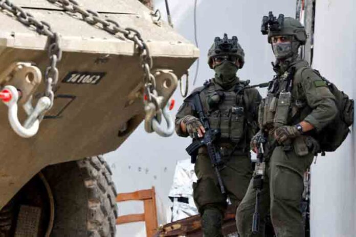 Israeli soldiers stand next to a military vehicle during an Israeli raid in Jenin, in the Israeli-occupied West Bank.