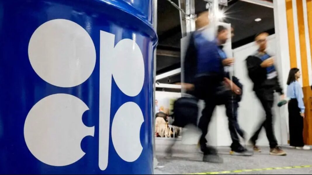 People walk past an installation depicting a barrel of oil with the logo of the Organization of the Petroleum Exporting Countries (OPEC).