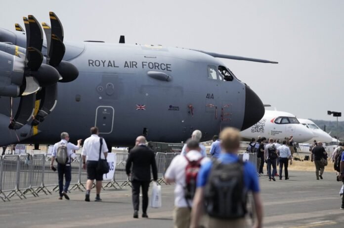 Visitors walk past planes at the Farnborough International Airshow in Farnborough, England, July 18, 2022.
